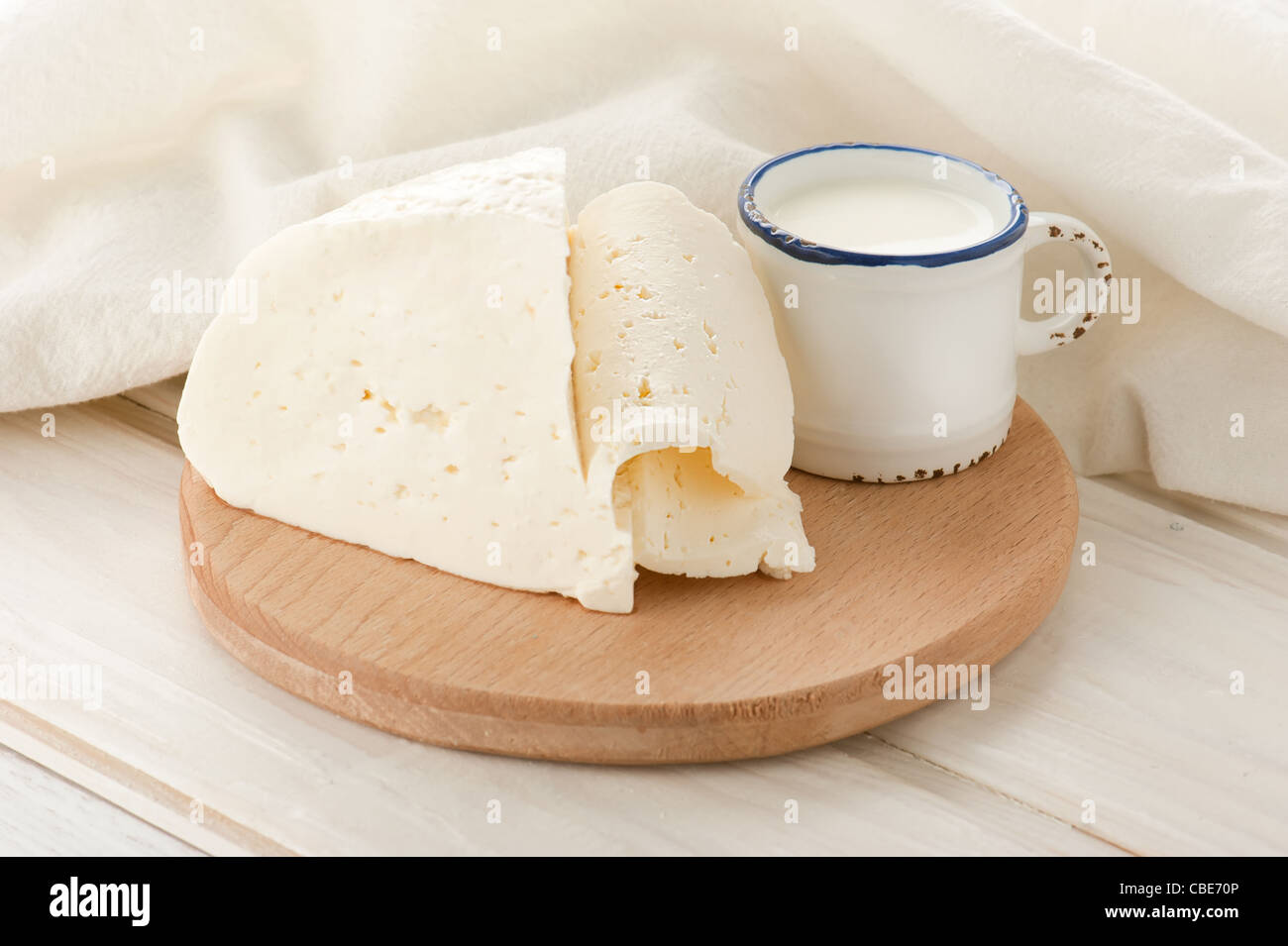 Breakfast with milk and soft sheep cheese on old wooden table with linen tablecloth Stock Photo