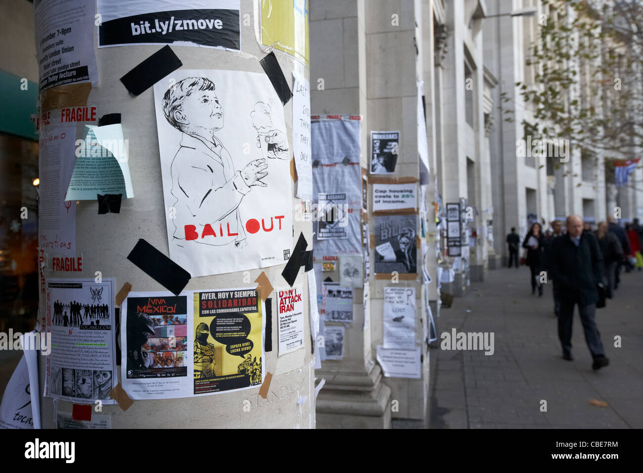 people walk past anti bail out posters and occupy protest outside st pauls in London England Uk United Kingdom Stock Photo