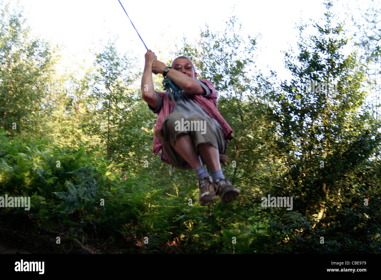 Man on a rope swing, Delamere Forest, Linmere, Cheshire, England, UK Stock Photo