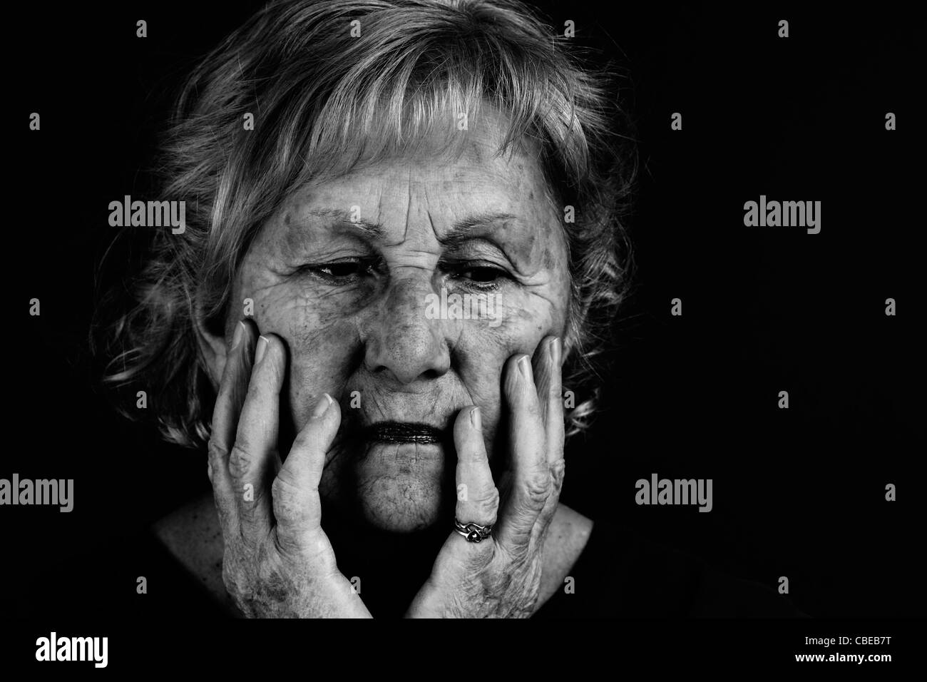 Creative low key black and white to emphasize dramatic facial expression of senior woman. Stock Photo