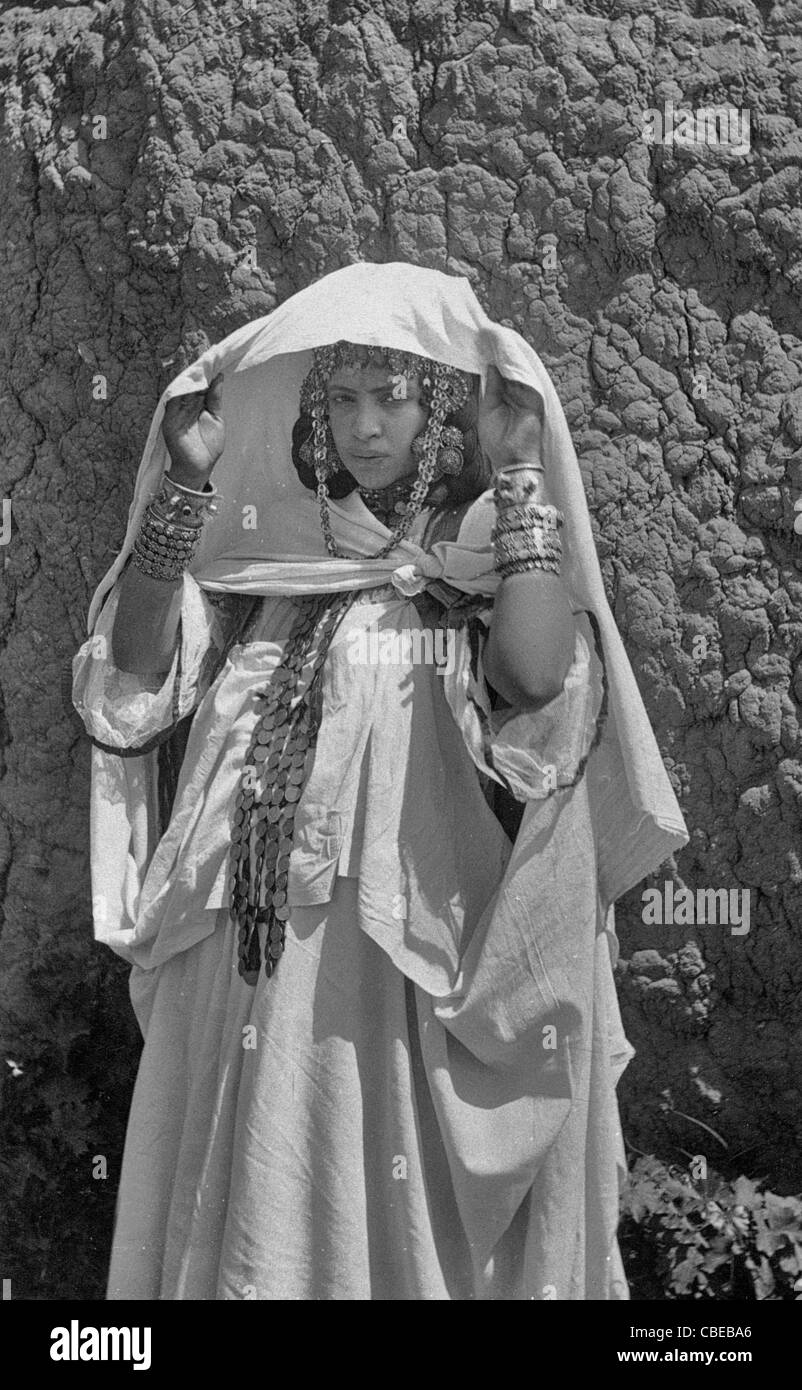 Woman, standing, facing front, wearing coin necklace, bracelets, and other jewelry, Algeria. Circa 1890 Stock Photo