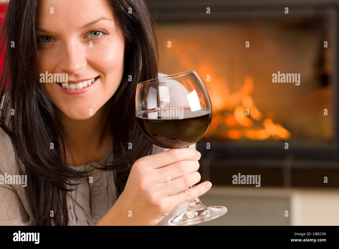 Young woman enjoying glass of red wine by home fireplace Stock Photo ...