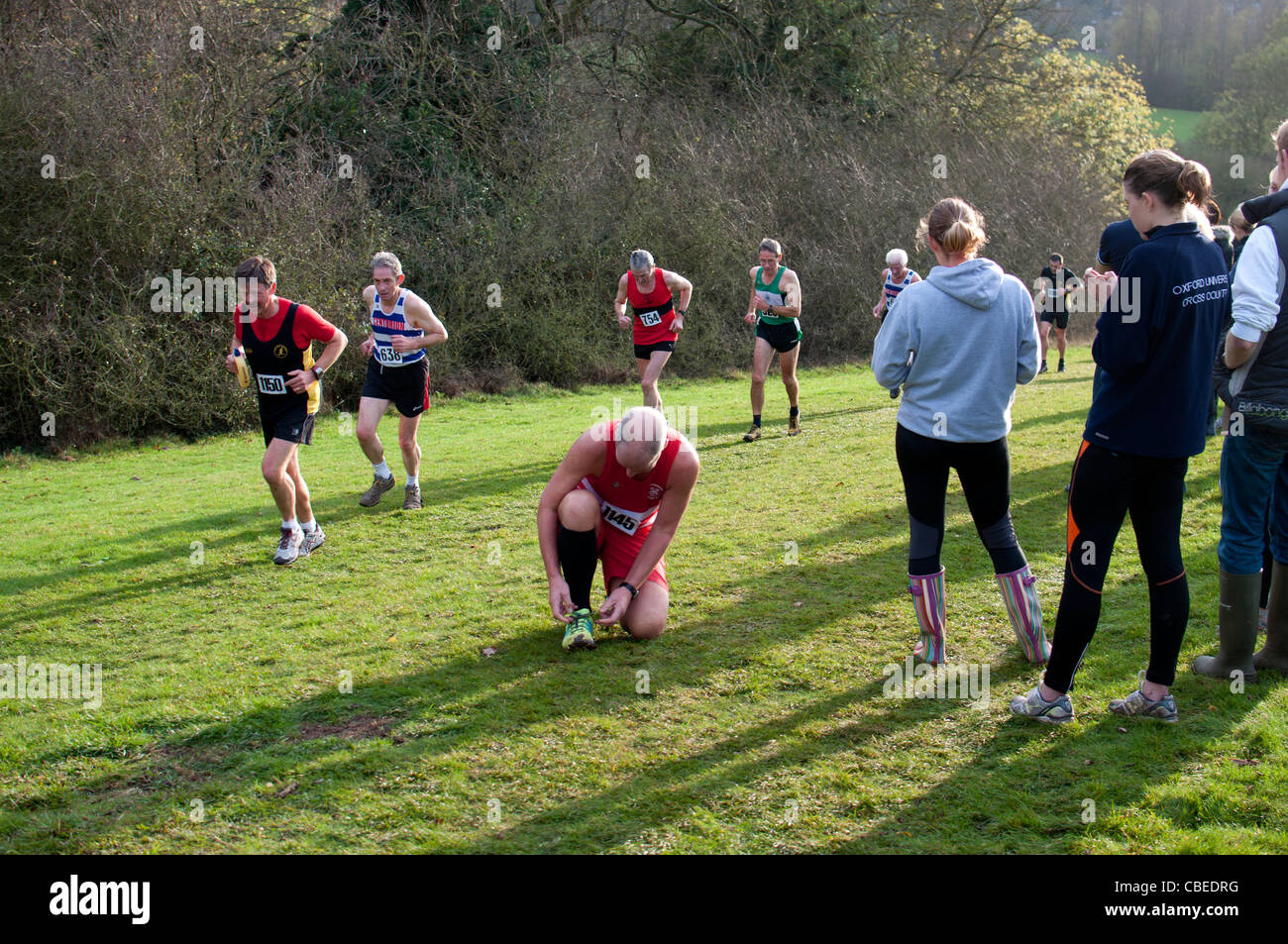 Man doing up shoelace during cross country race Stock Photo