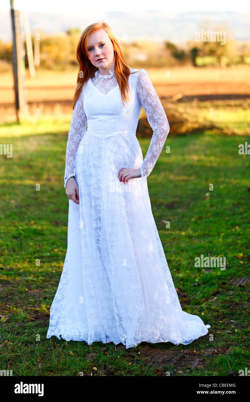 Teenage bride wearing a vintage wedding dress in a field Stock