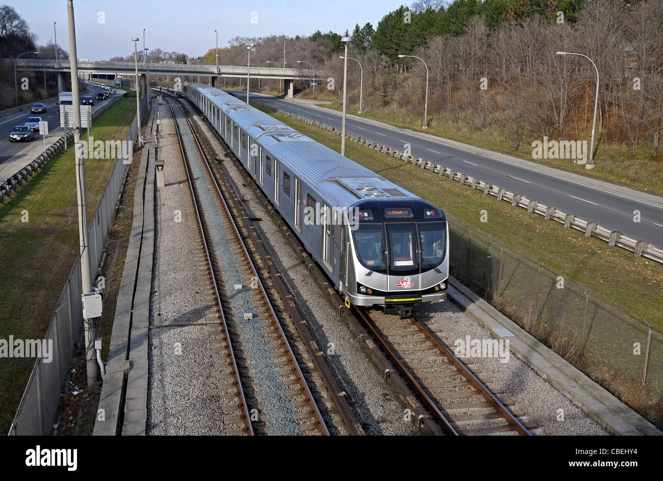 Toronto commuter subway train in open cut track area beside expressway