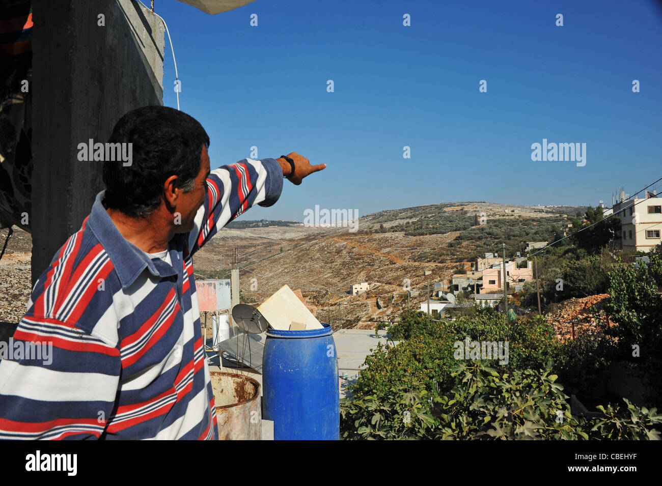 Palestinian families traumatized by the coming of the Israeli colonists., Adel shows the nearby colony, the source of violence. Stock Photo