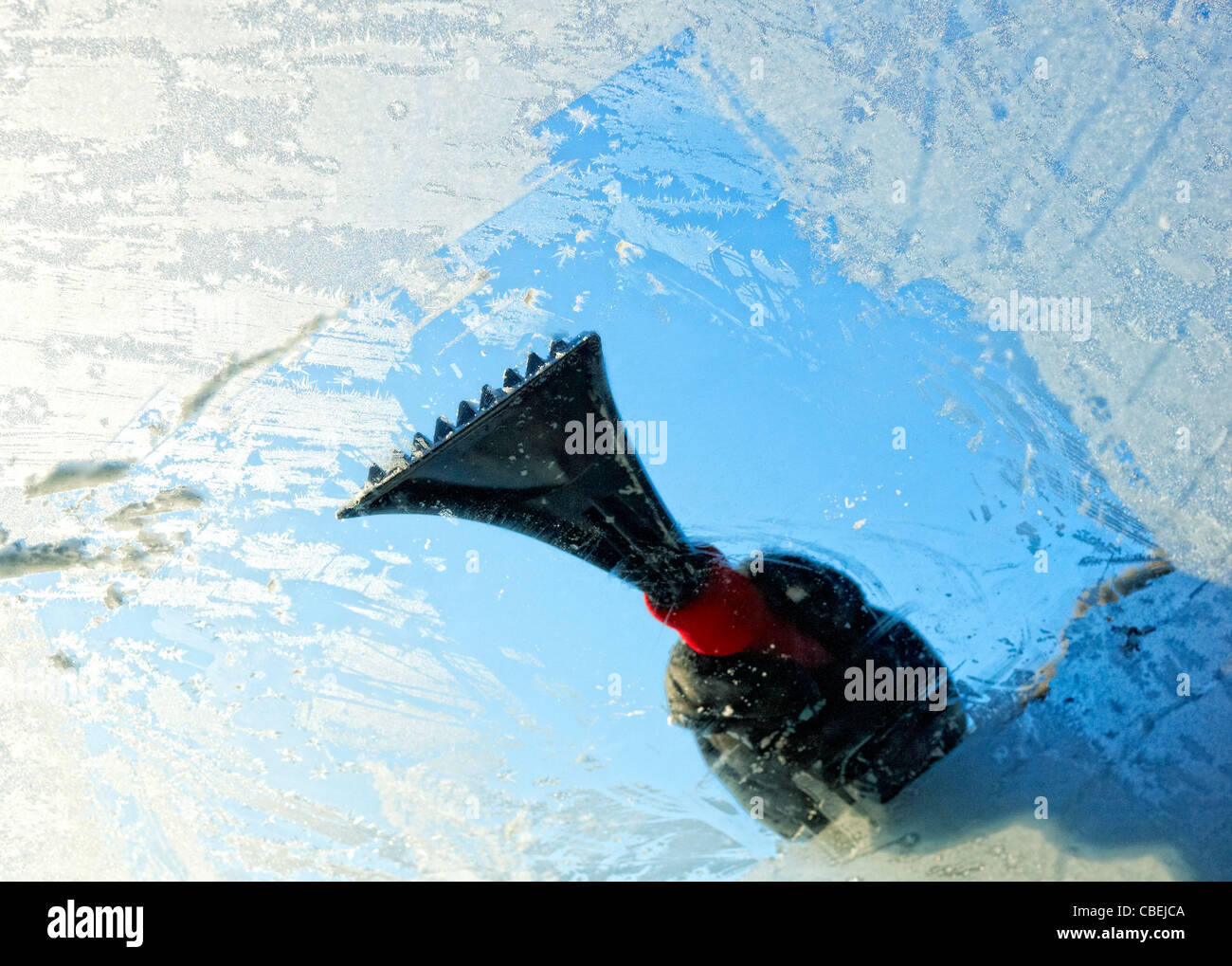 Scraping ice from a car windscreen, view from inside. Stock Photo