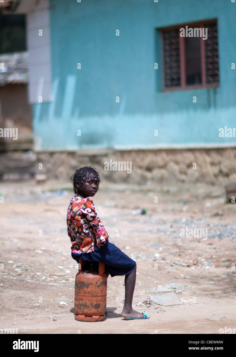 Girl Sitting On A Bottle Of Gas, Huambo, Angola Stock Photo