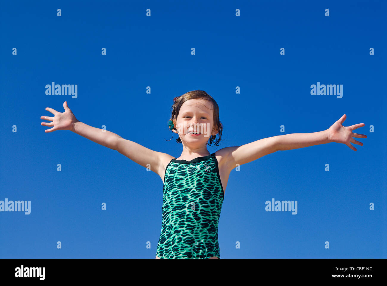 Joyous girl in bathing suit and open arms at the beach. Stock Photo