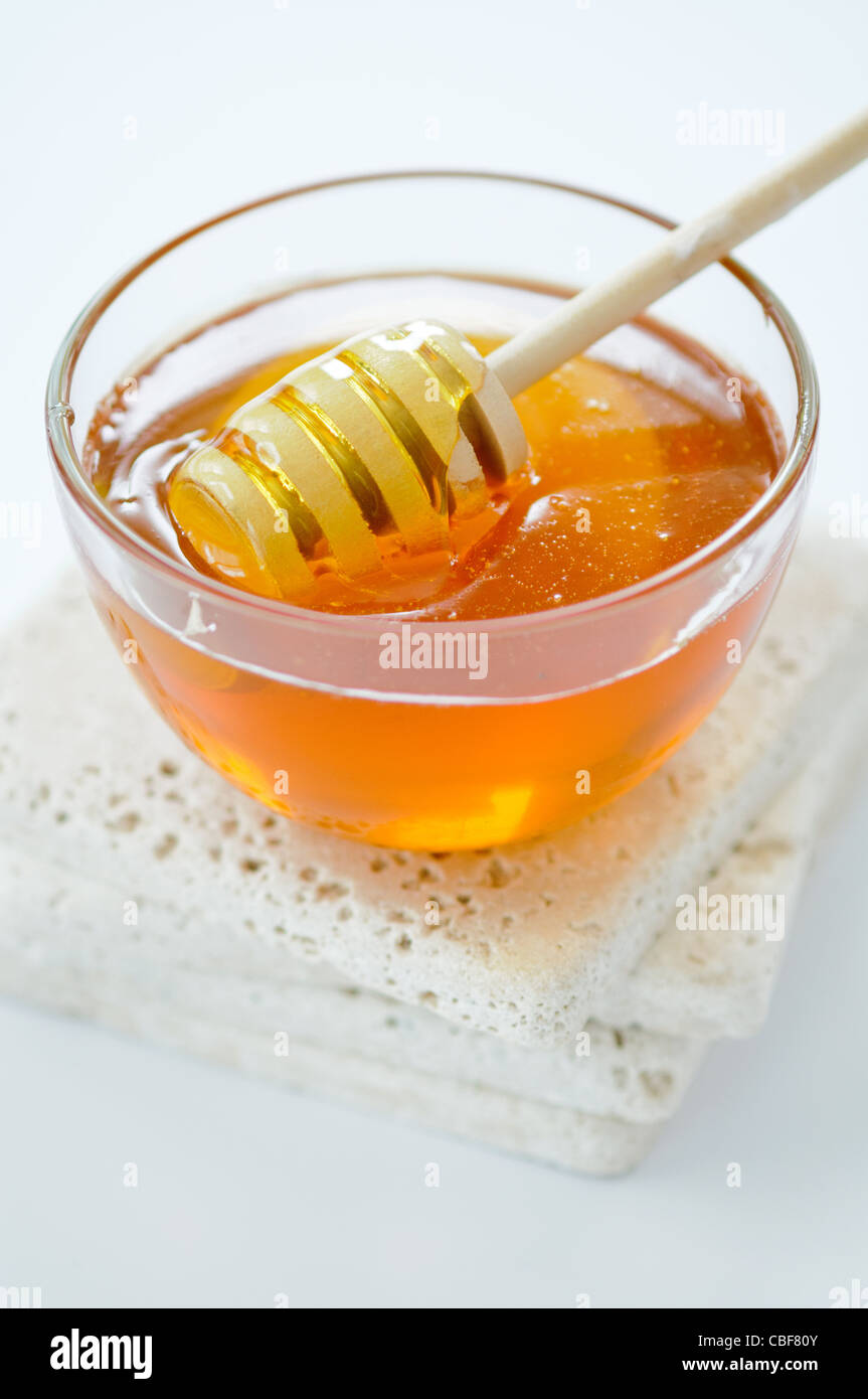 Bowl of runny honey with honey dipper Stock Photo Alamy