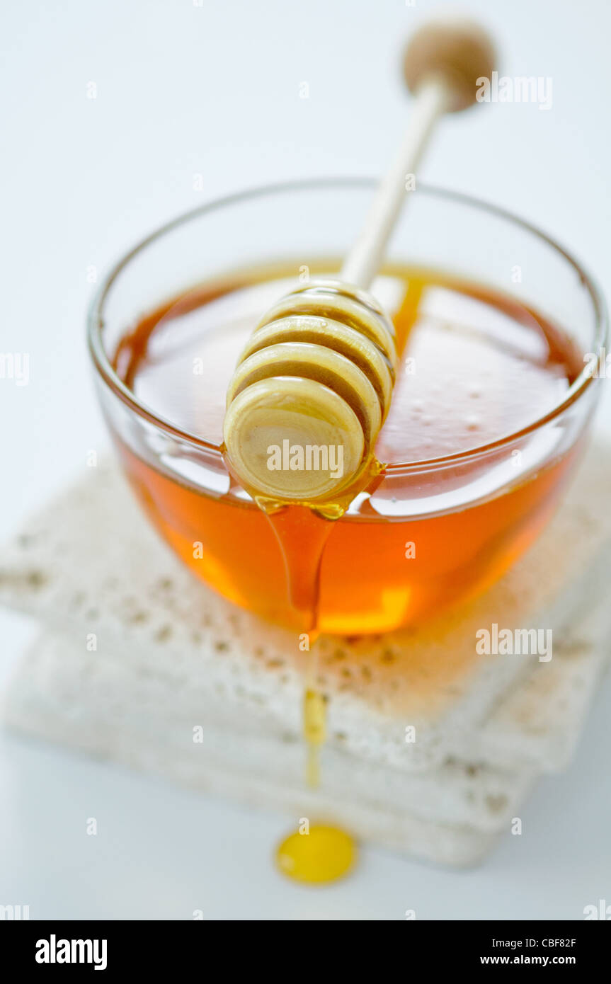 Bowl of runny honey with honey dipper Stock Photo