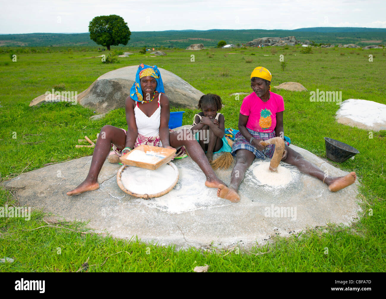 Women And Girl Grinding Grain, Village Of Caconda, Angola Stock Photo