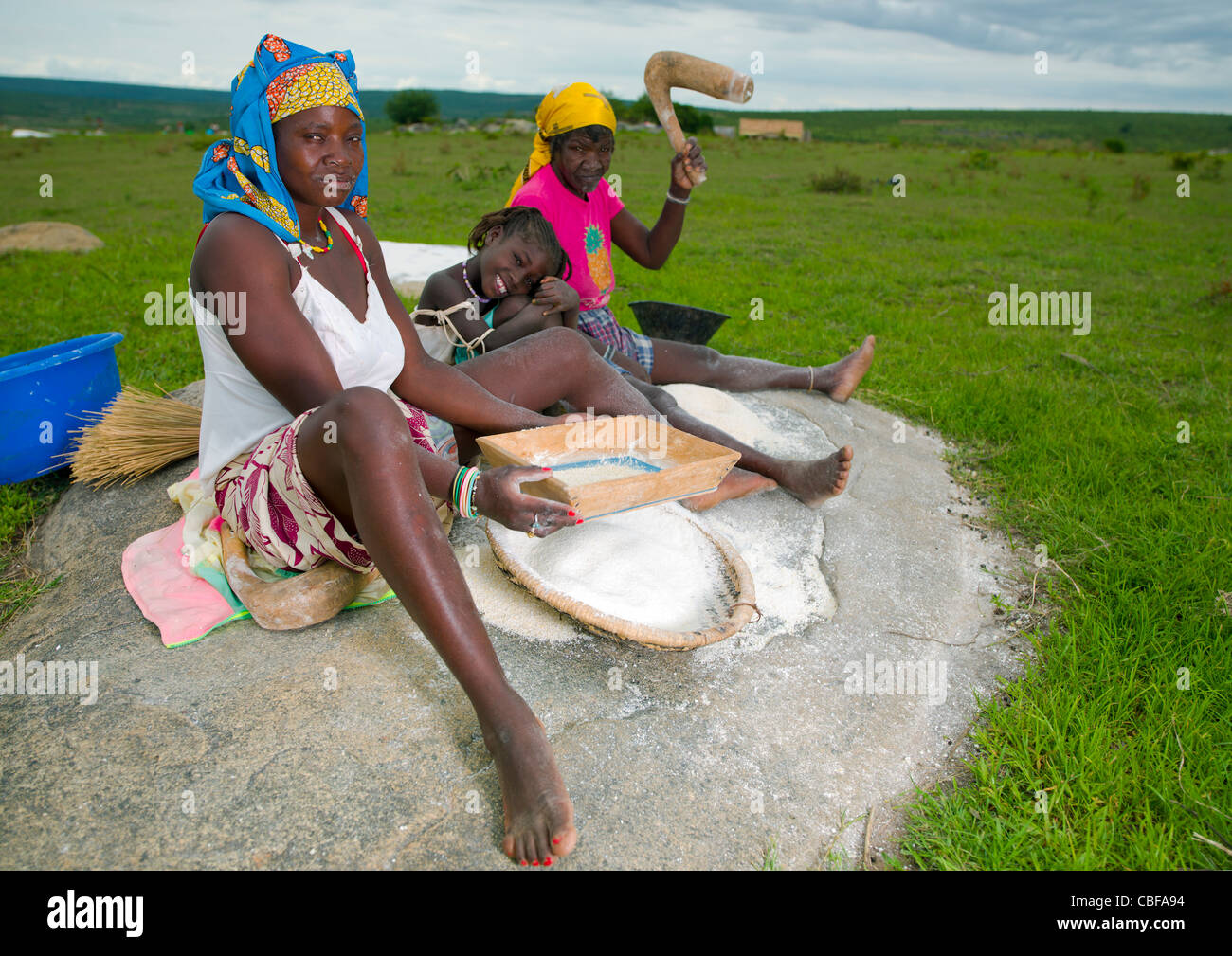 Women And Girl Grinding Grain, Village Of Caconda, Angola Stock Photo