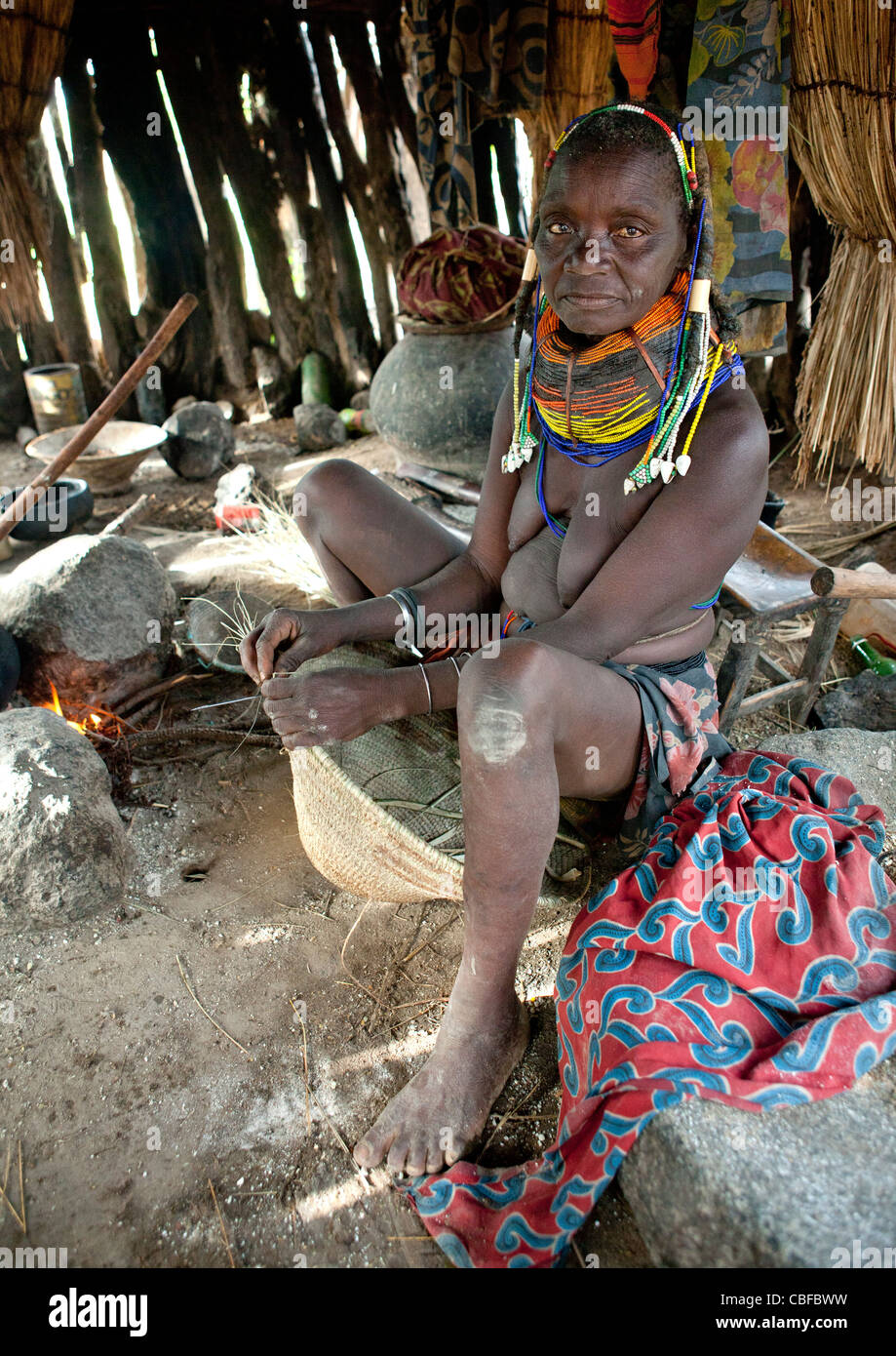 Old Mwila Woman Cooking In Her Hut, Chibia Area, Angola Stock Photo