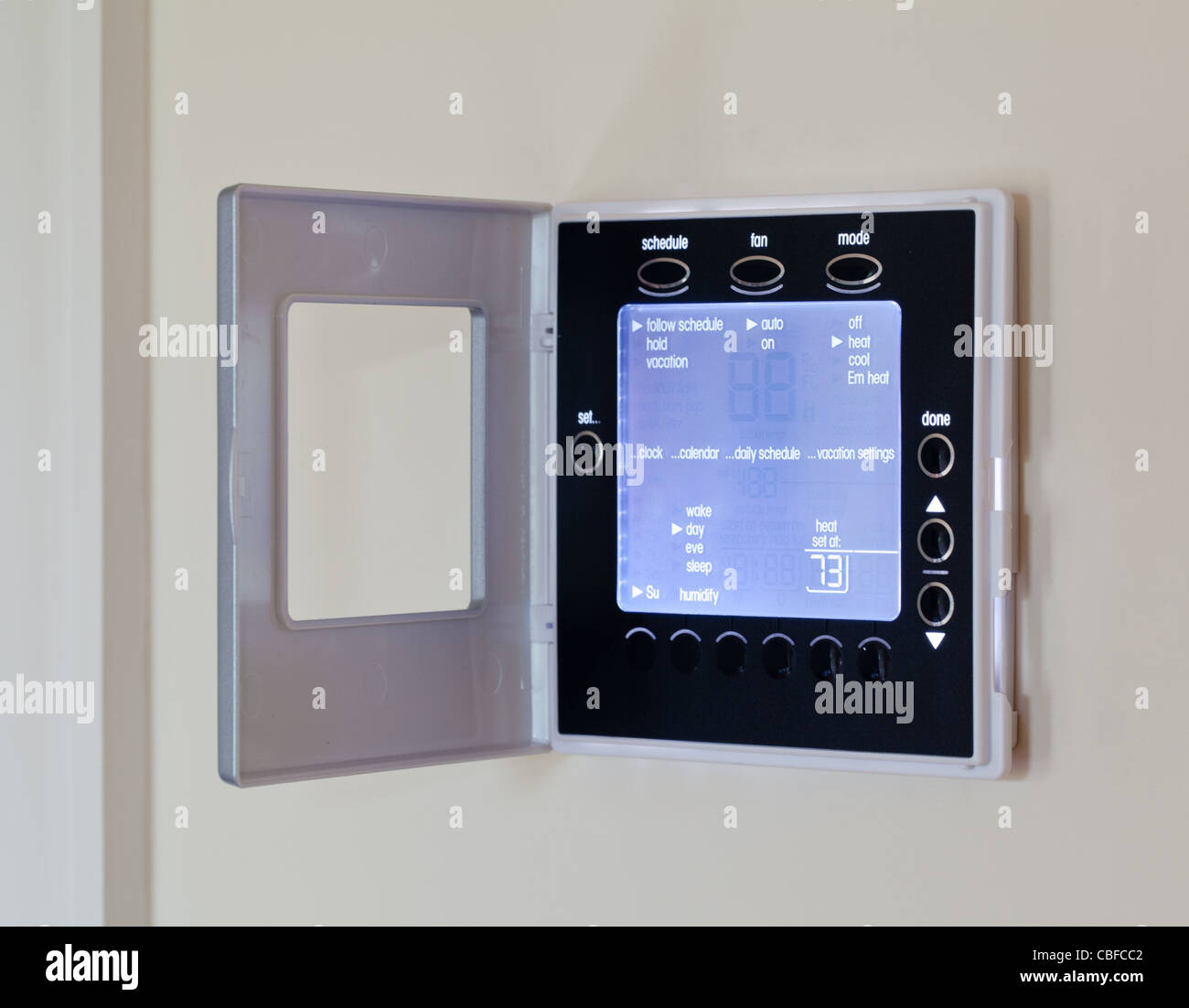 Electronic thermostat with blue LCD screen for controlling air conditioning and heating HVAC Stock Photo