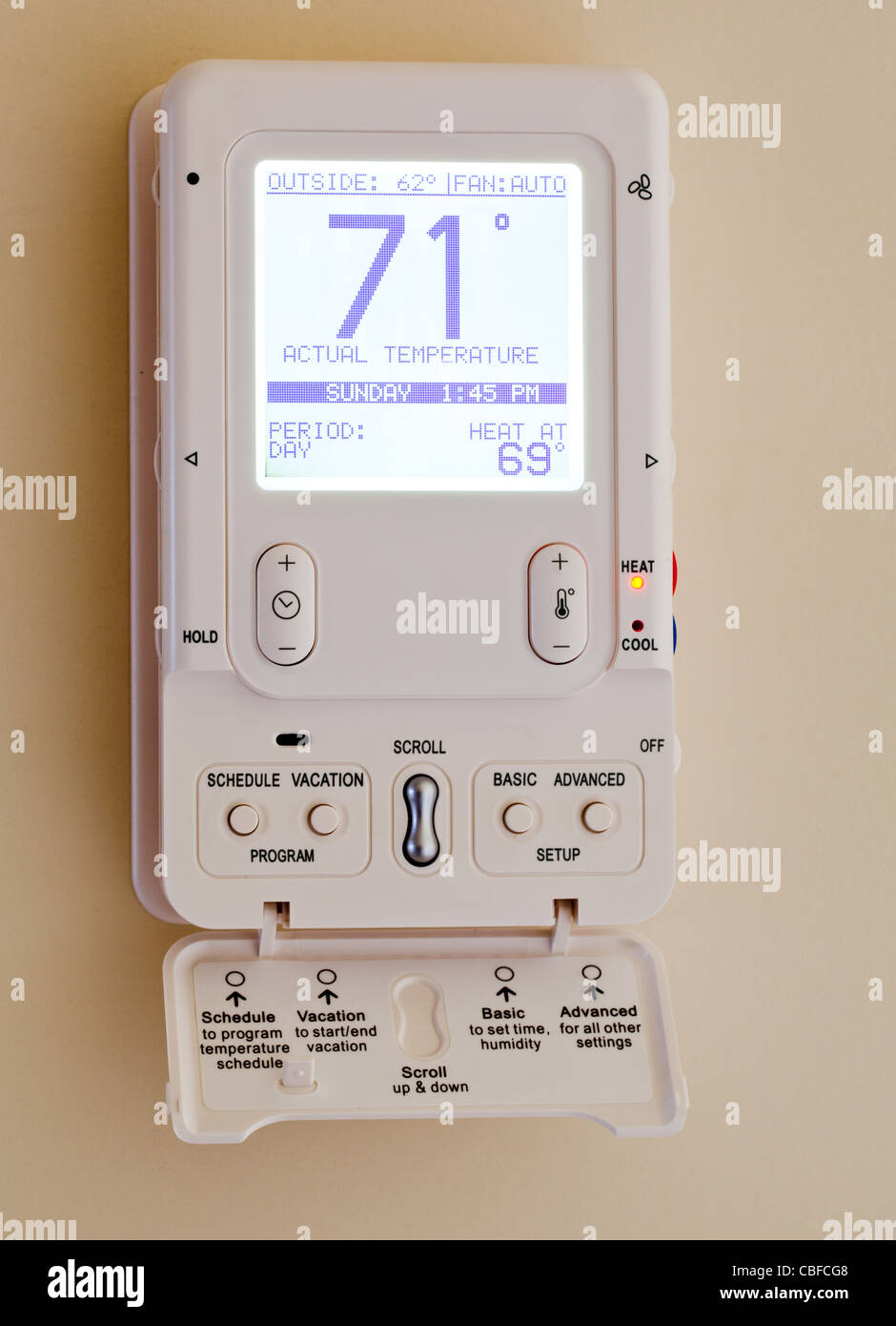 Electronic thermostat with blue LCD screen for controlling air conditioning and heating HVAC Stock Photo