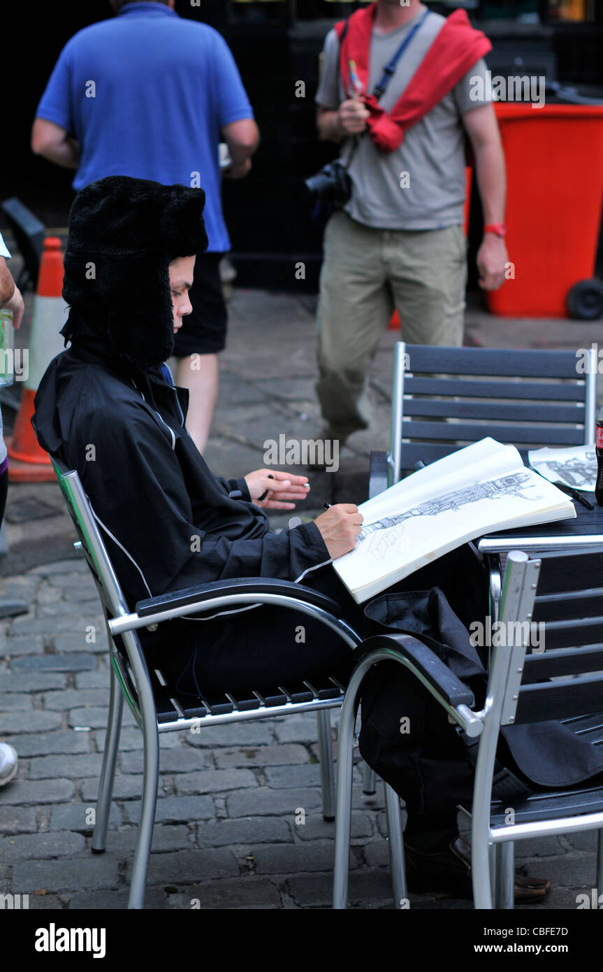 An artist sits outside a café drawing Canterbury Cathedral. Stock Photo