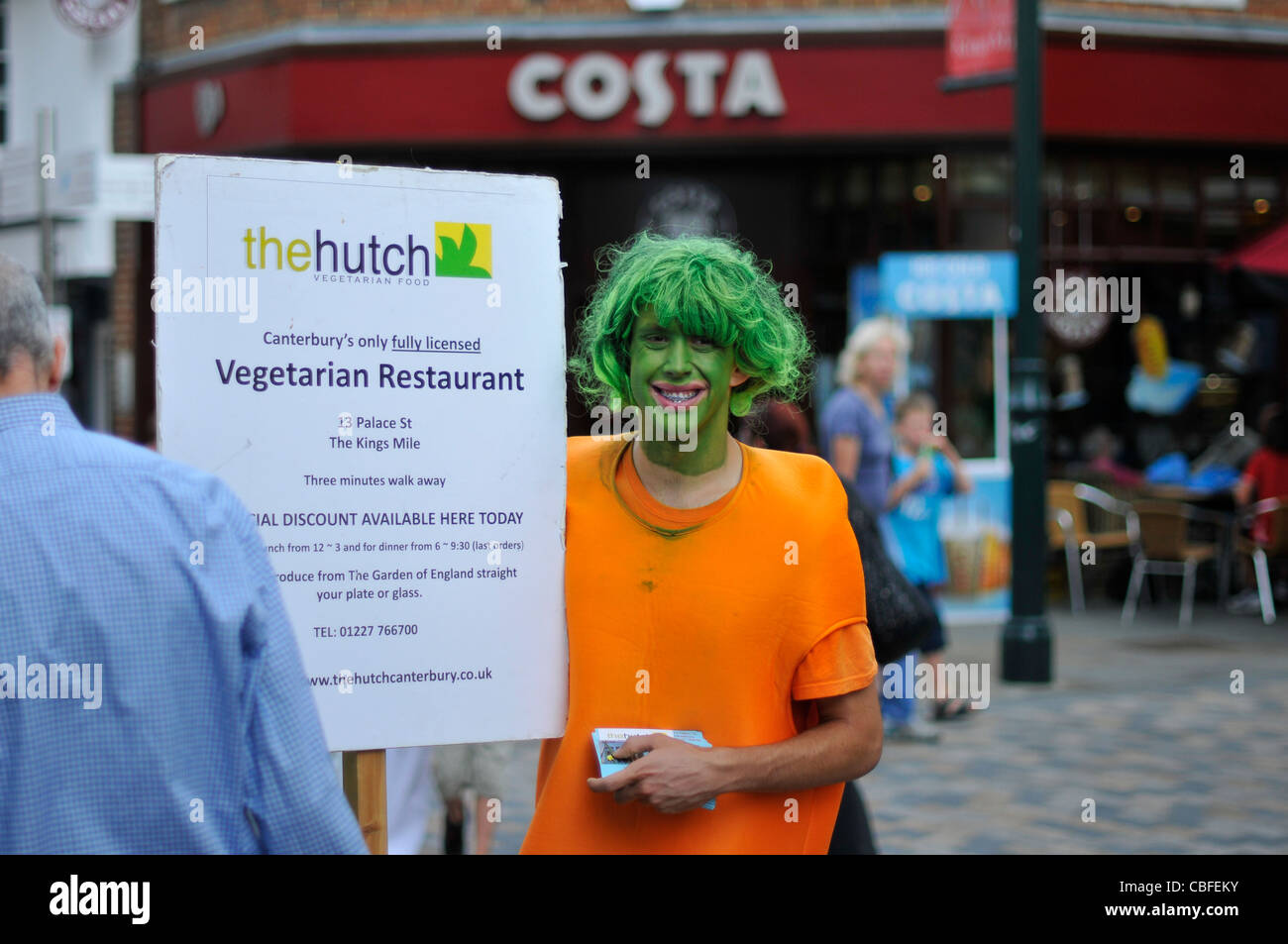 Man advertises a vegetarian restaurant in Canterbury whilst dressed as a carrot. Stock Photo