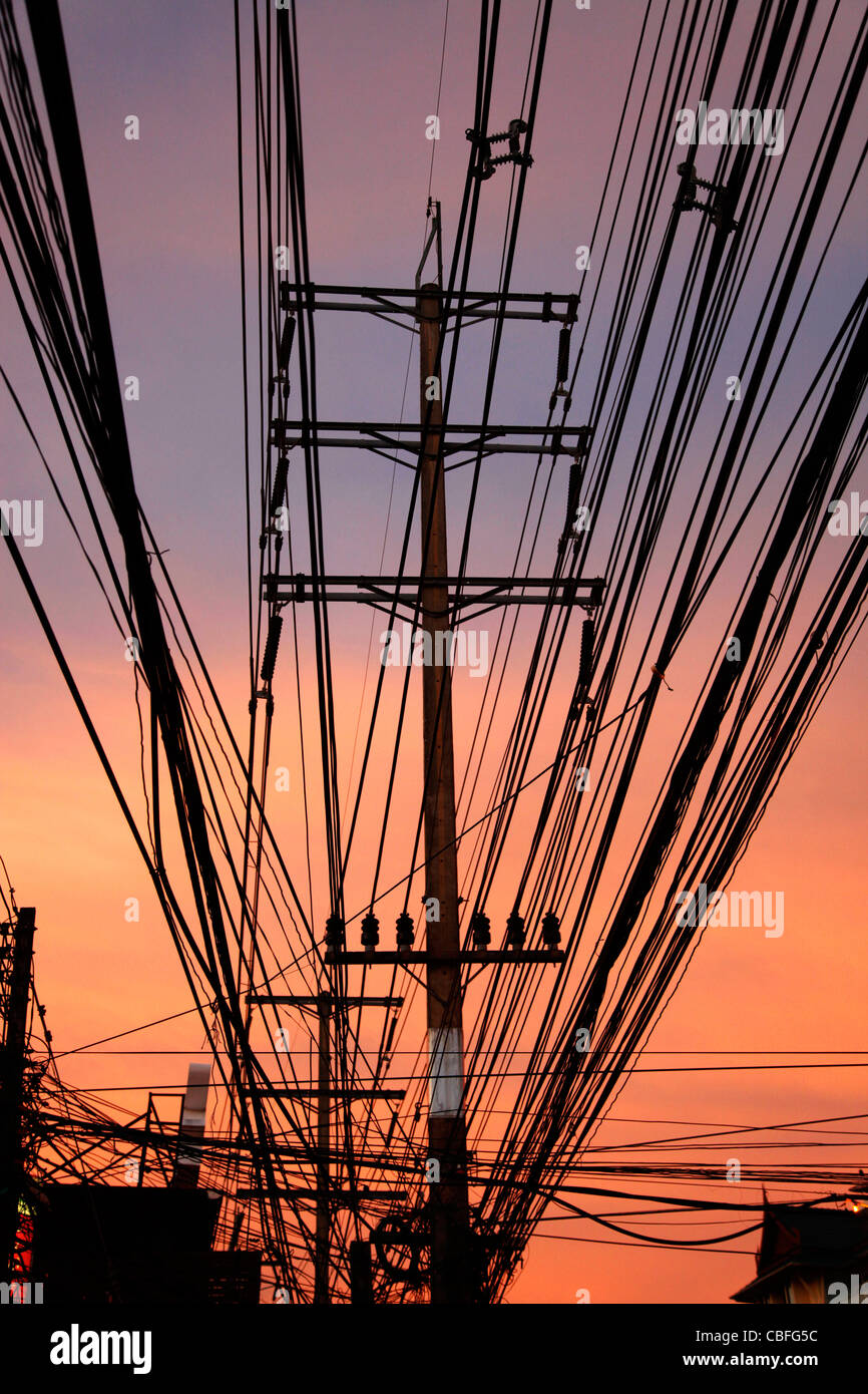 Silhouette of electrical power lines and electricity cables at sunset in Patong, Phuket, Thailand Stock Photo