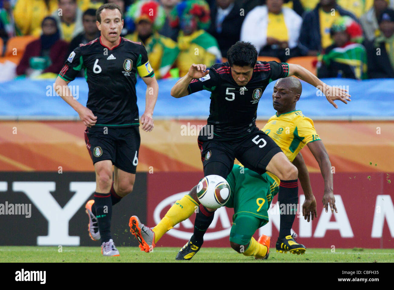 Katlego Mphela of South Africa (R) battles against Ricardo Osorio of Mexico (L) during the opening match of the FIFA World Cup. Stock Photo