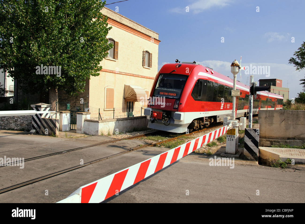 Italian train going over level crossing in the town of Ceglie Messapica Stock Photo