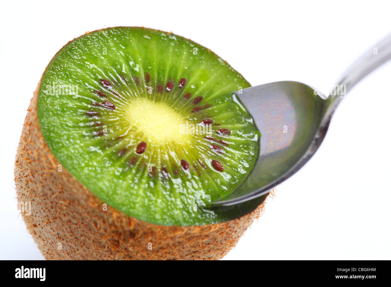 A sliced kiwi fruit, complete with spoon ready to eat Stock Photo