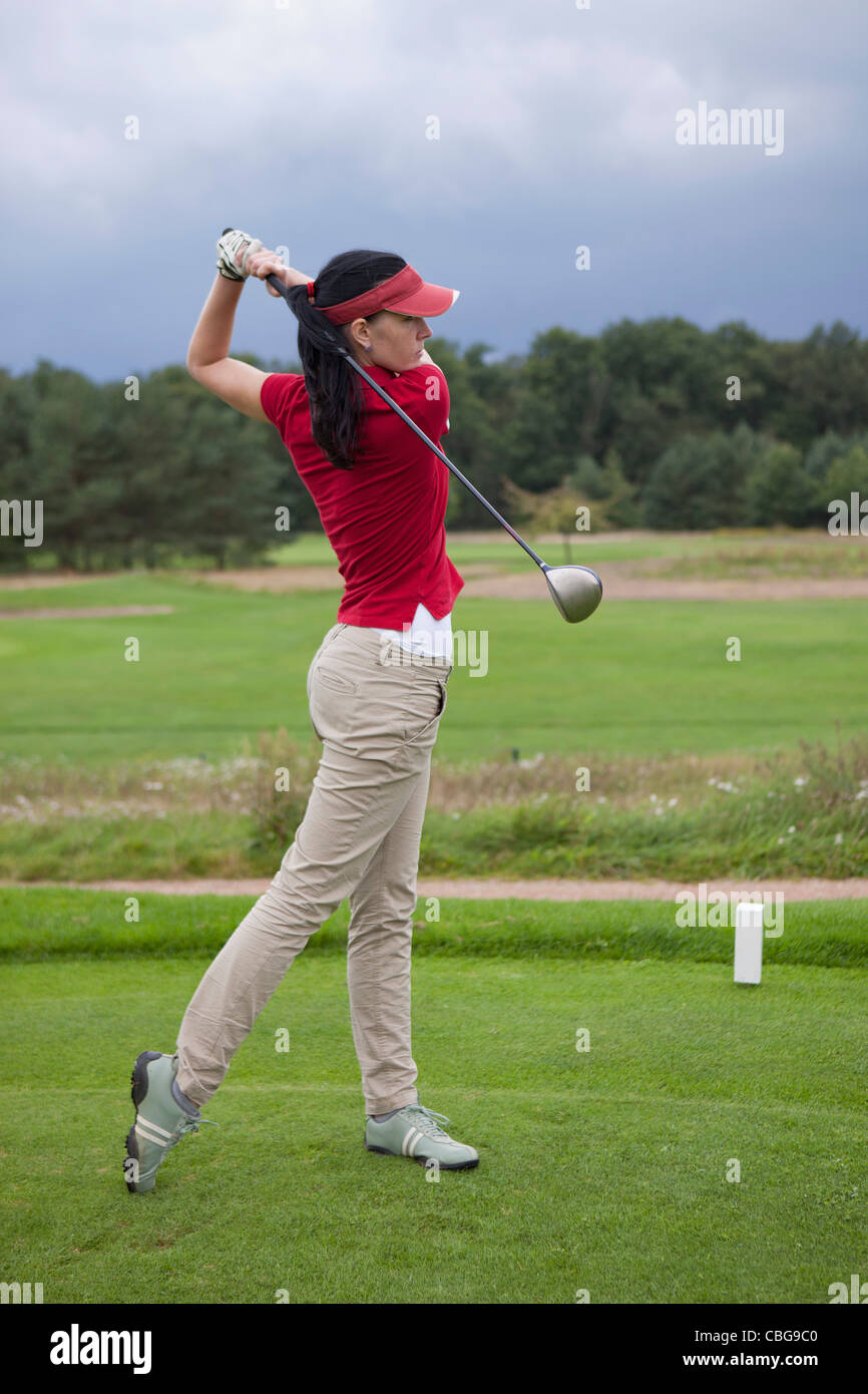 A female golfer teeing off Stock Photo