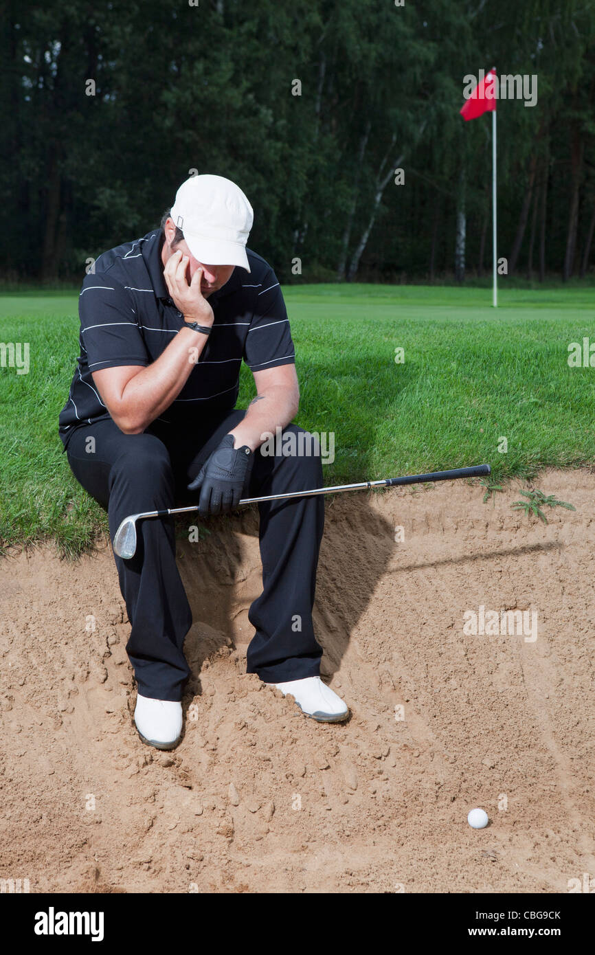 An unhappy golfer sitting at the edge of a sand trap Stock Photo Alamy
