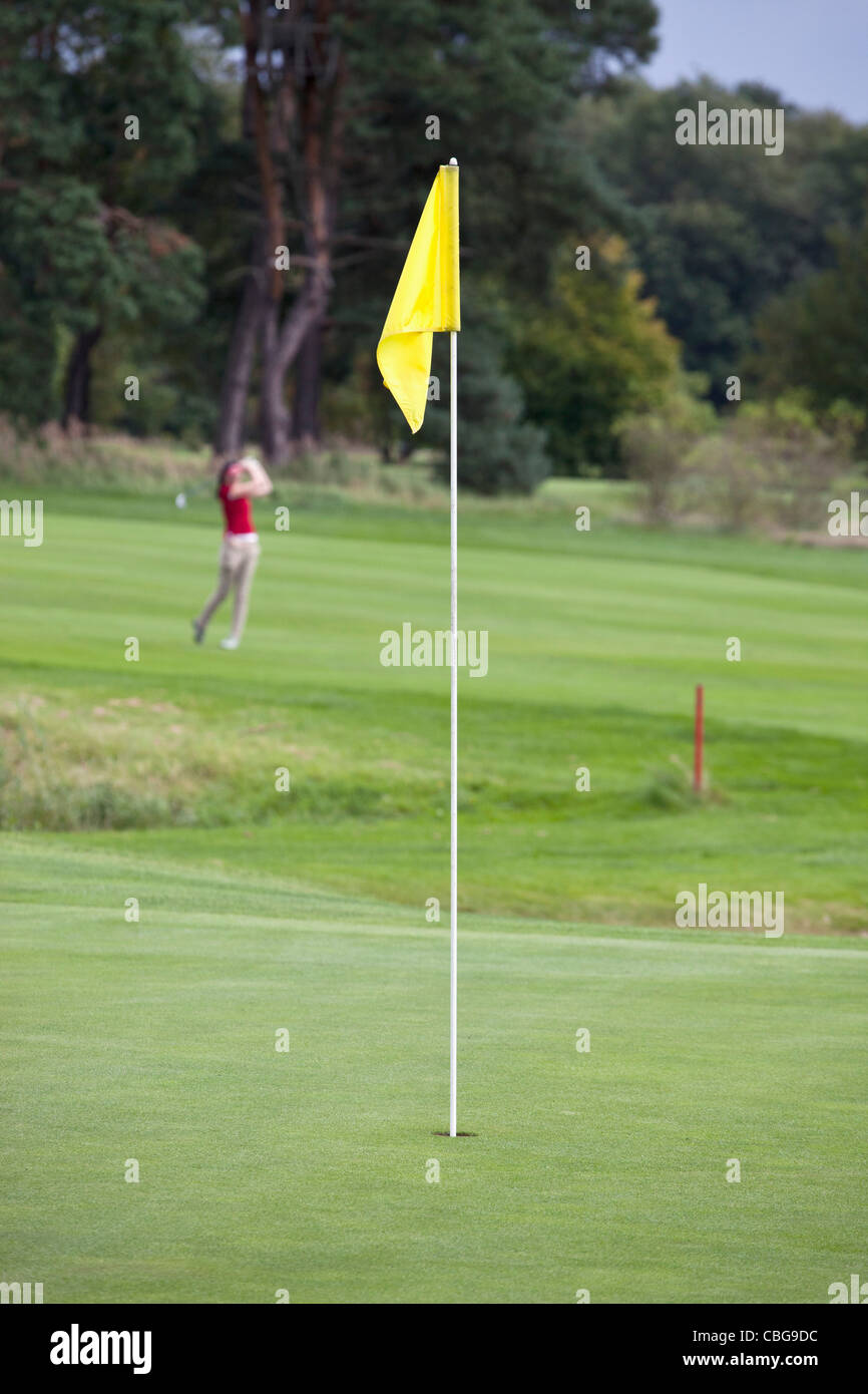 A putting green with flag, golfer swinging in distance Stock Photo Alamy