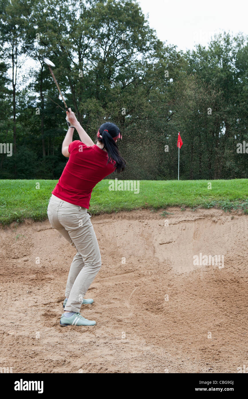 A female golfer hitting a ball out of a sand trap Stock Photo Alamy