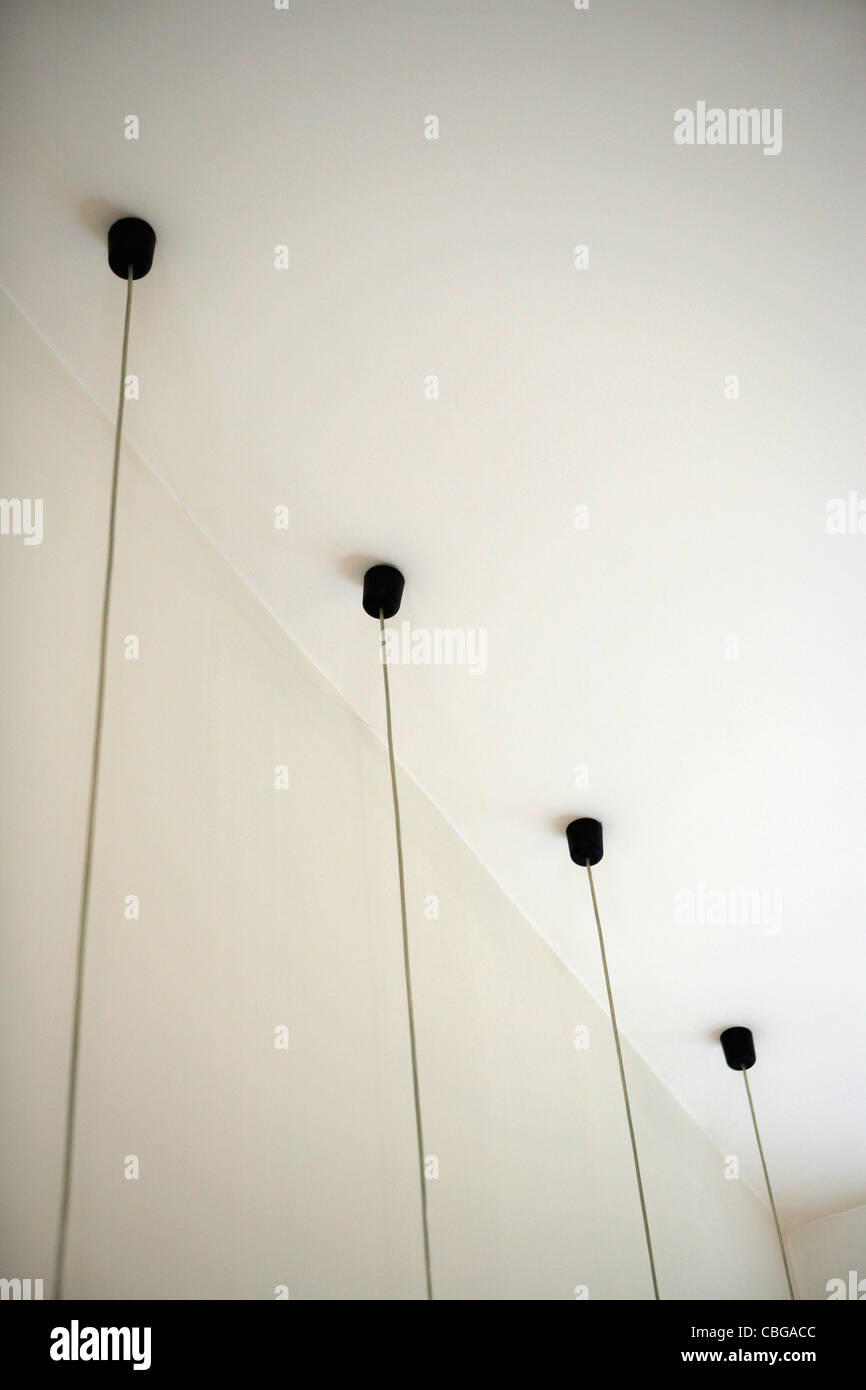 Four light fixtures with cables hanging down from ceiling Stock Photo