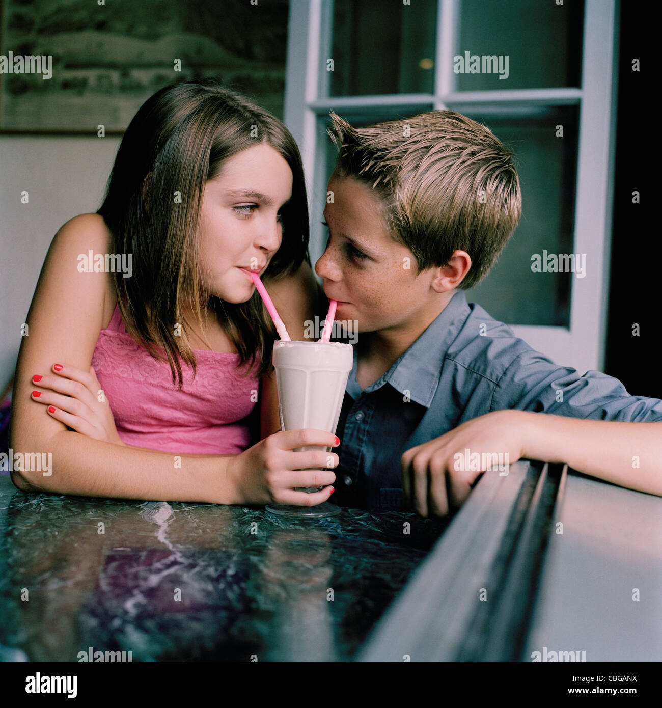 A Young Teenage Couple Sharing A Milkshake At A D