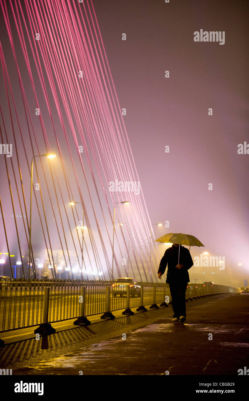 A man walking along a city street, holding an umbrella Stock Photo - Alamy