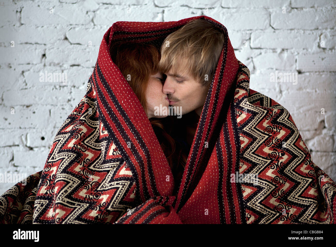 A young couple wrapped in a blanket kissing Stock Photo Alamy