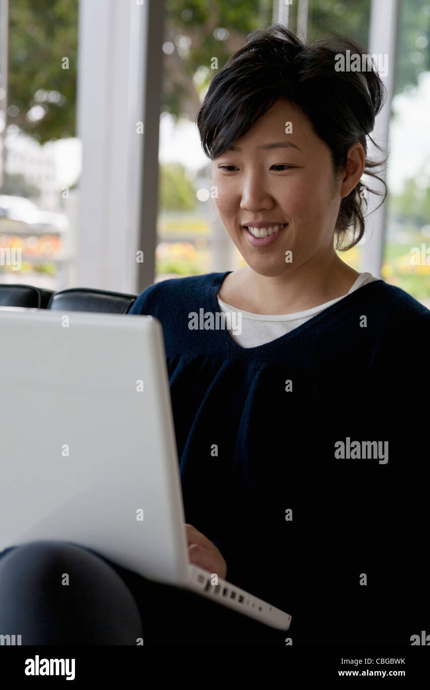 A young woman sitting on a sofa using a laptop Stock Photo - Alamy