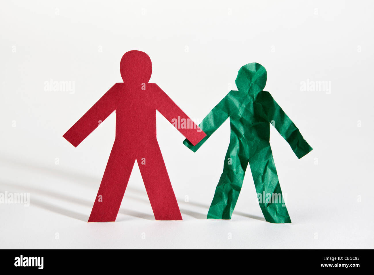 Two paper dolls holding hands, one crumpled Stock Photo Alamy
