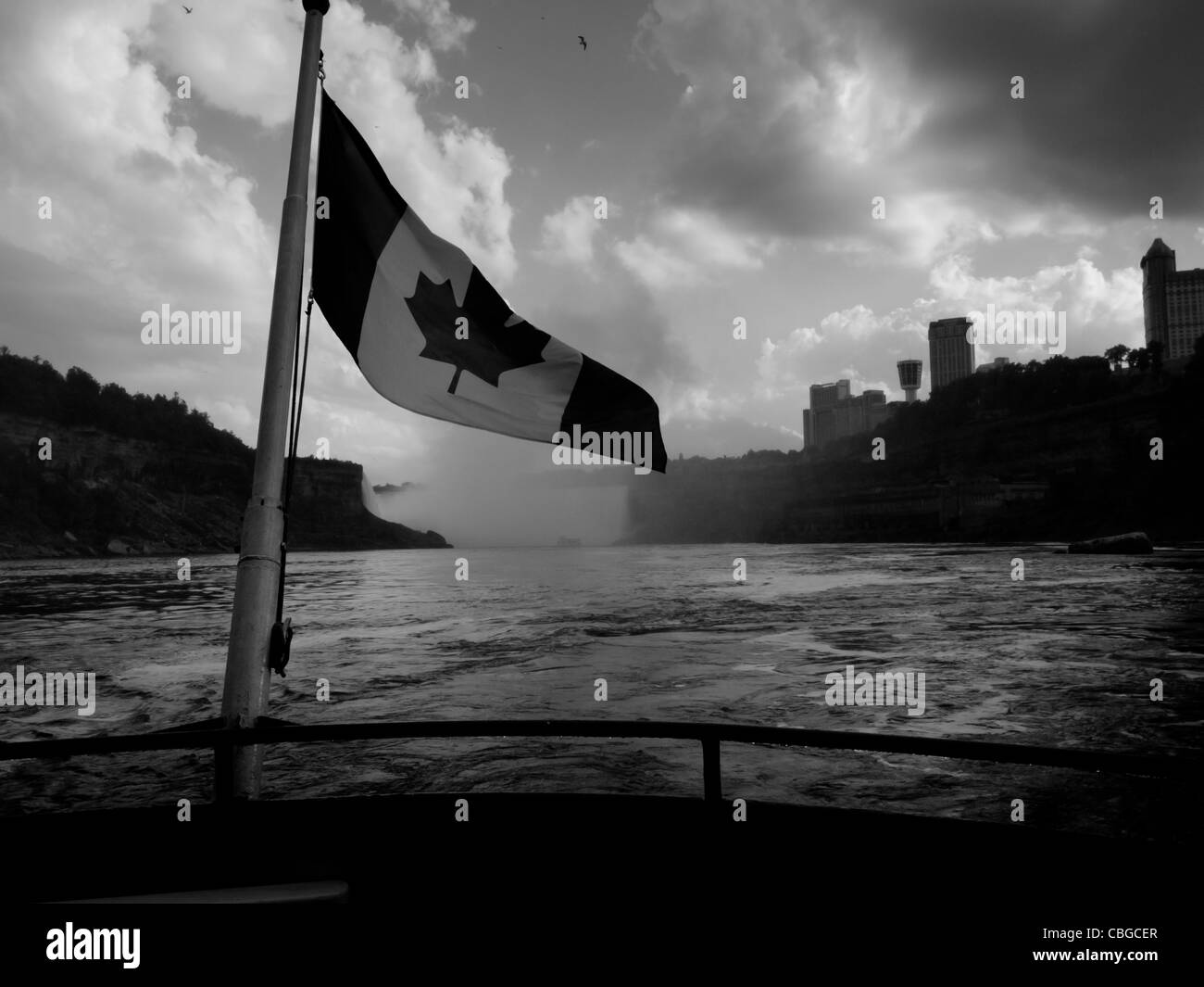 The Canadian flag flaps from the back of a tour boat with Niagara Falls