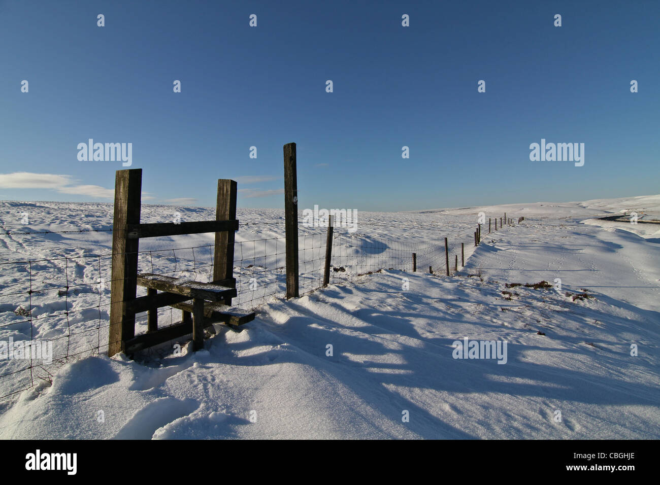 A stile across a fence high in the deeply snow covered Pennine Hills Stock Photo