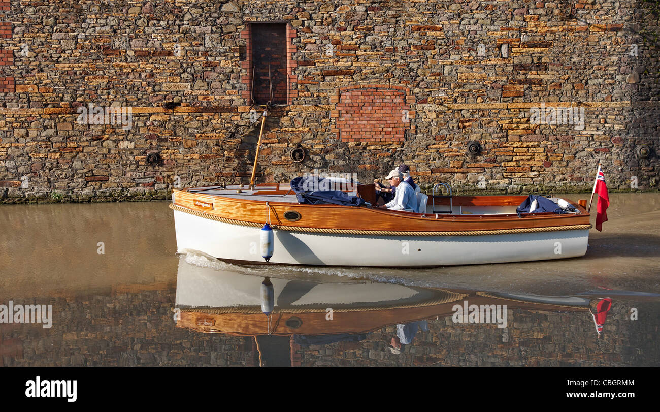 Small motor boat sailing down the still waters of the floating harbour