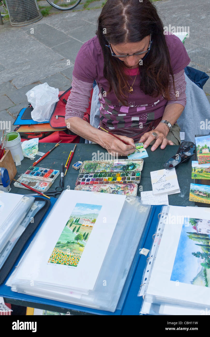An Italian female artist paints miniature paintings for sale on the street in Siena, Italy. Stock Photo