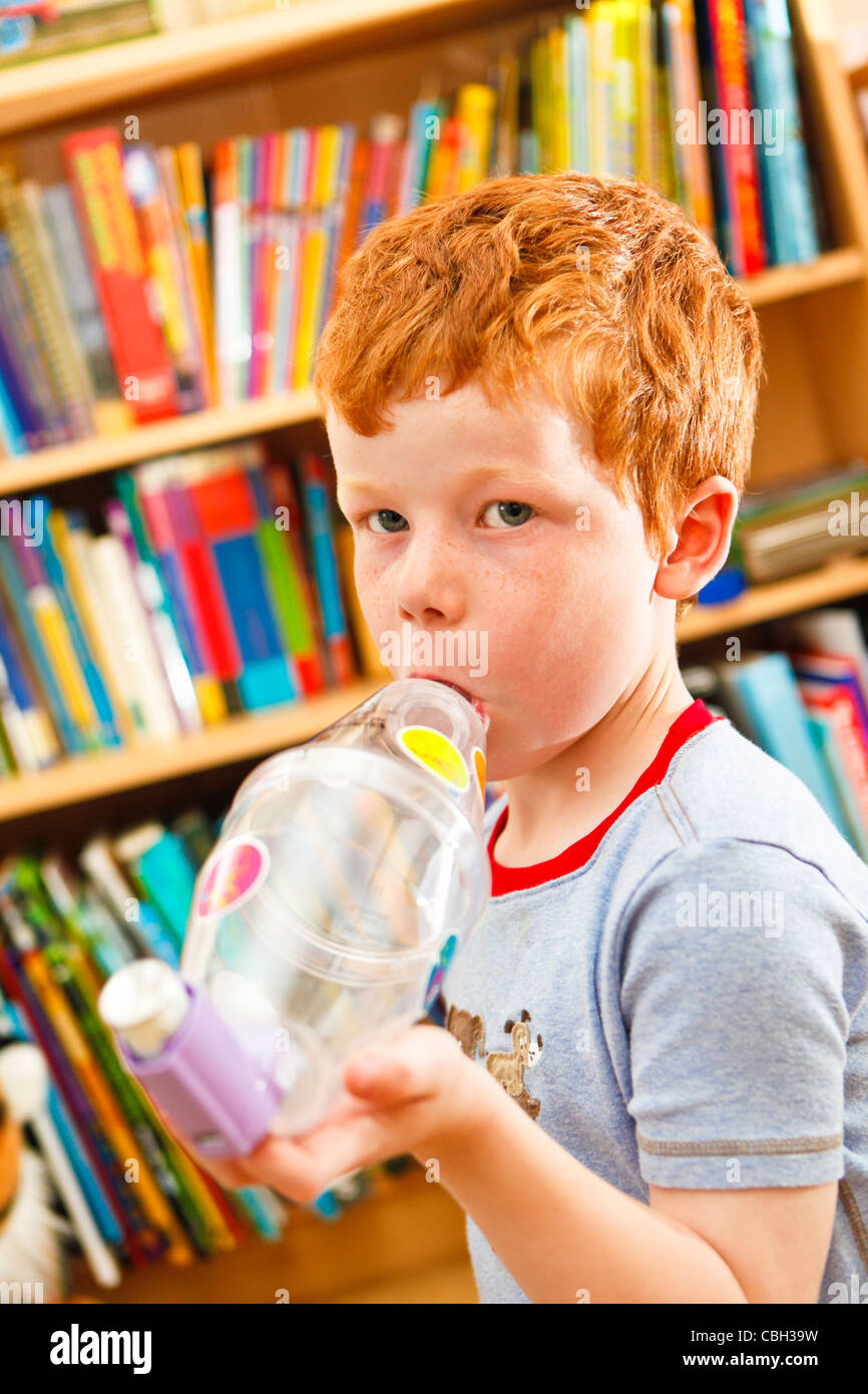 Young boy, aged 7, using an inhaler to combat asthma. Self medicating. Stock Photo