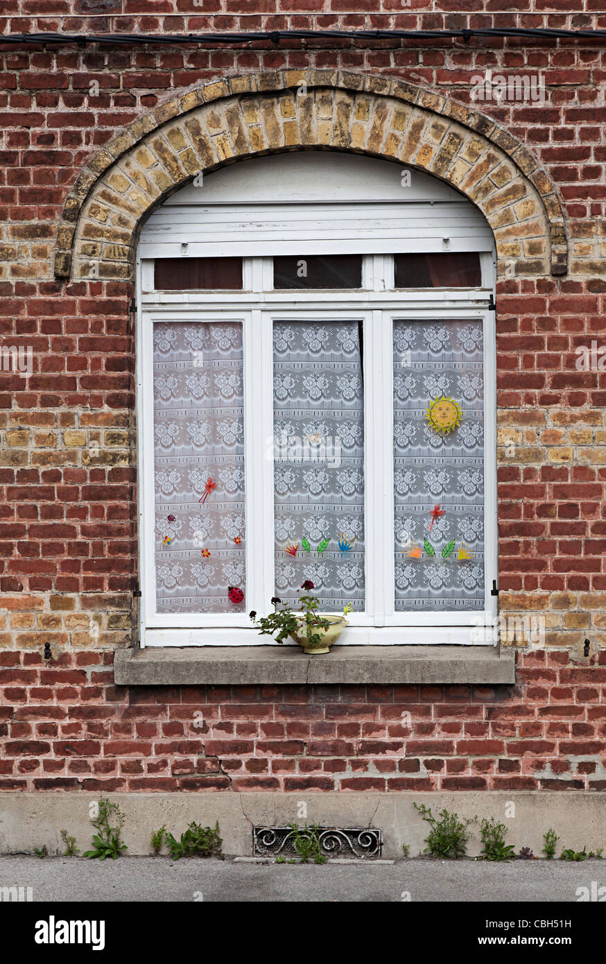 Window in old red brick wall with lace curtains Bergues France Stock Photo