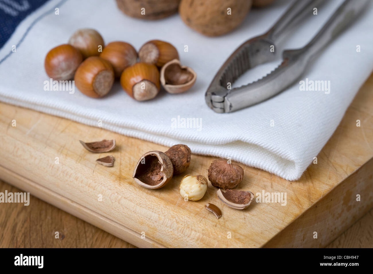 hazel nuts and walnuts on a chopping board with nut crackers and walnuts Stock Photo