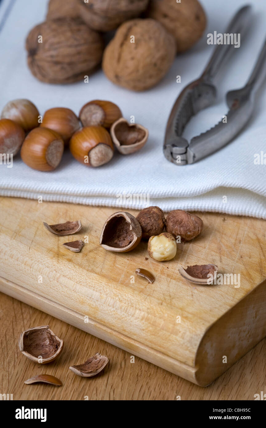 hazel nuts and walnuts on a chopping board with nut crackers and walnuts Stock Photo