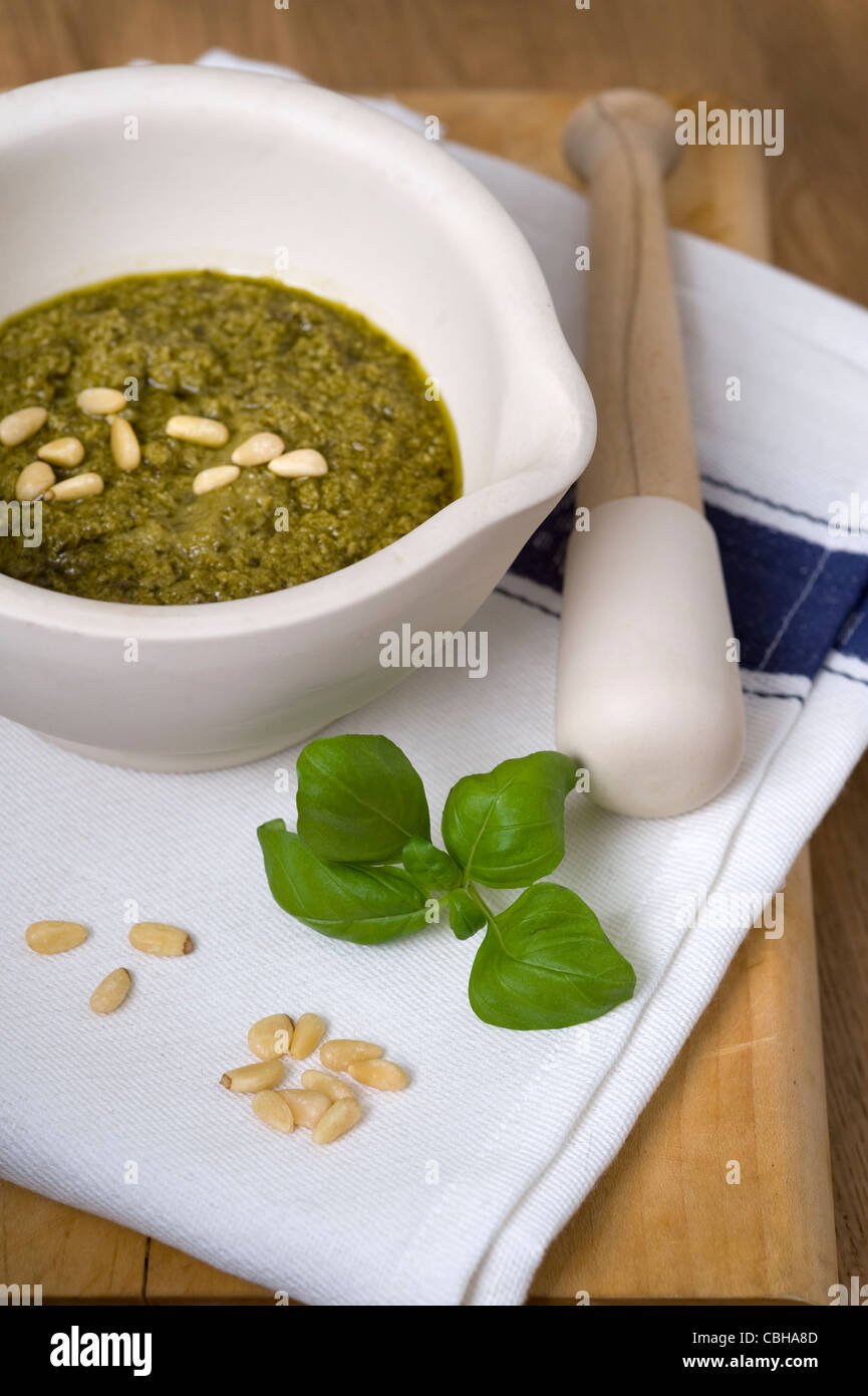 preparing pesto using pine nuts and basil with a pestle and mortar Stock Photo