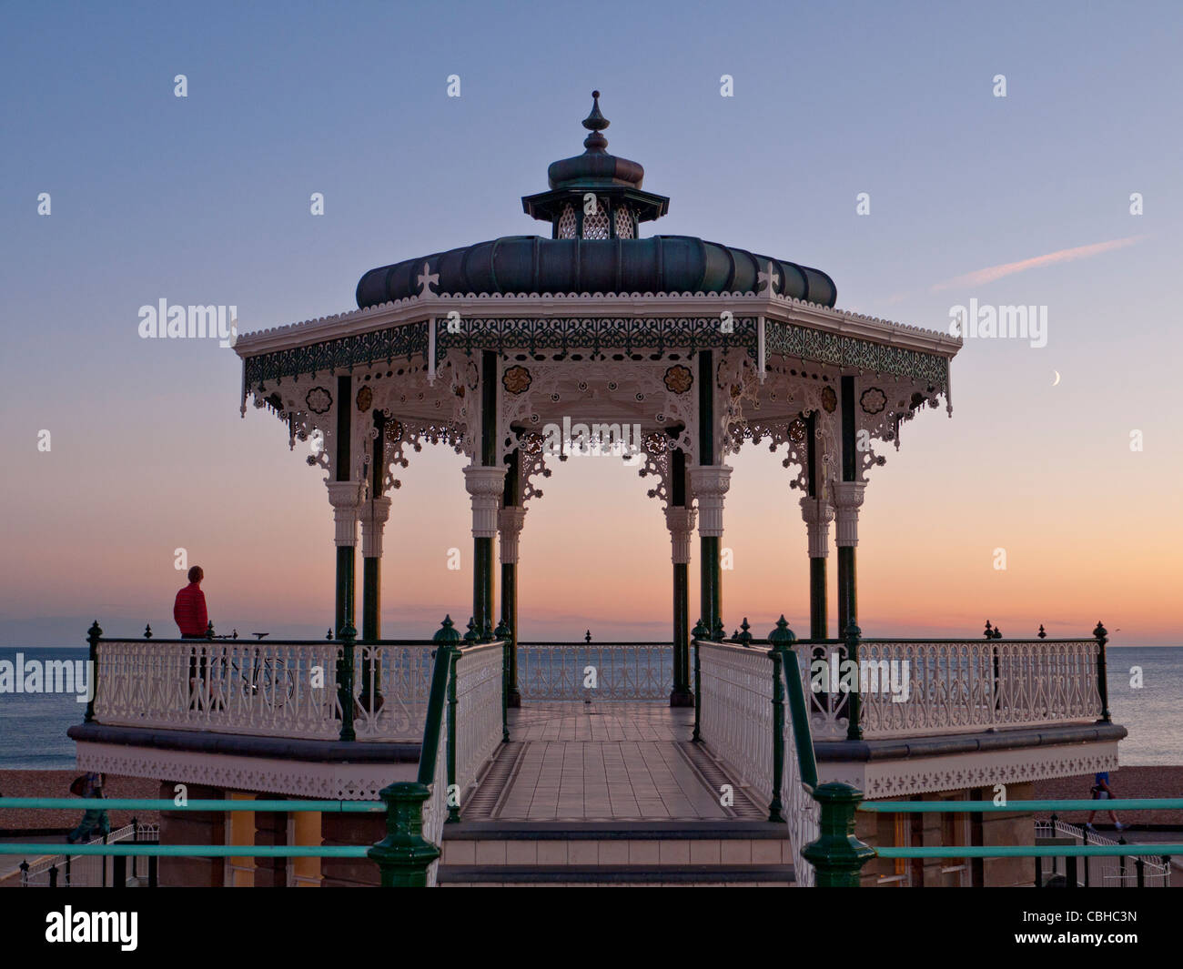 BRIGHTON Victorian Bandstand on the promenade at sunset with lone figure enjoying the wide seascape view Brighton Sussex UK Stock Photo