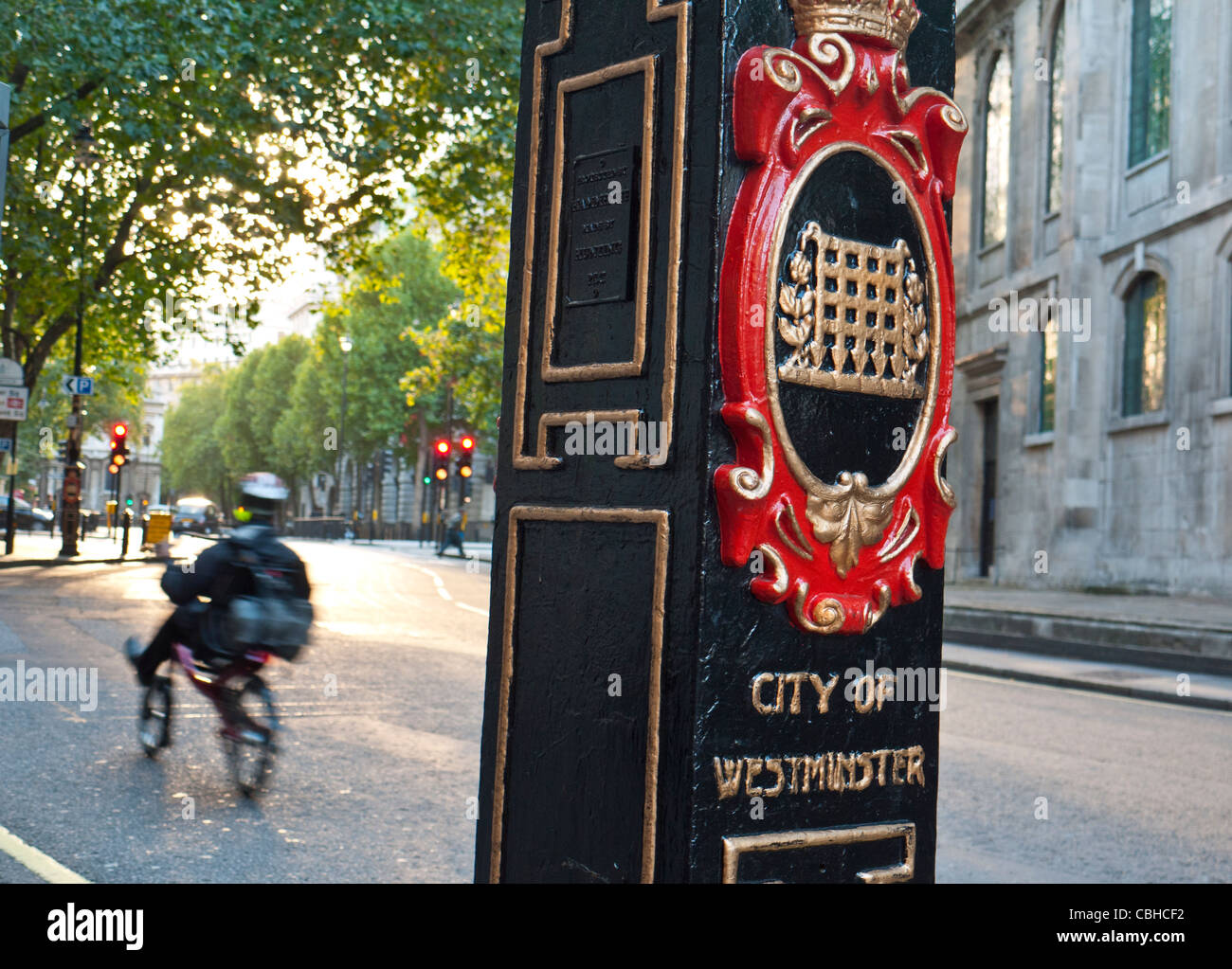 Ornate post with heraldic coat of arms with passing cyclist at boundary entrance to the City of Westminster Holborn London UK Stock Photo