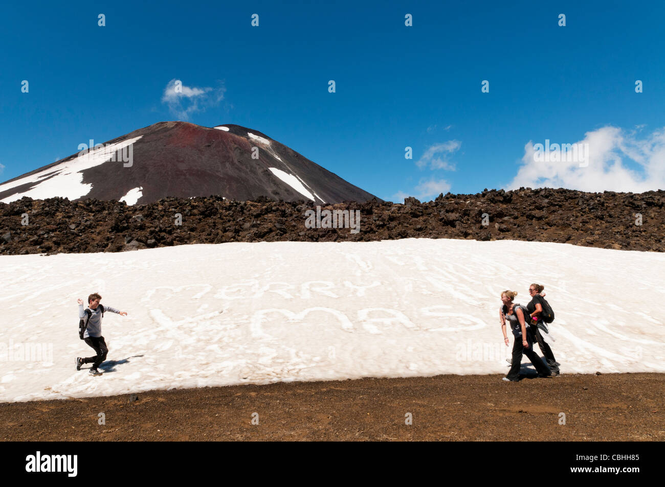 backpackers having a snow ball fight with merry christmas written in snow, in summeTongariro crossing National Park, New Zealand Stock Photo