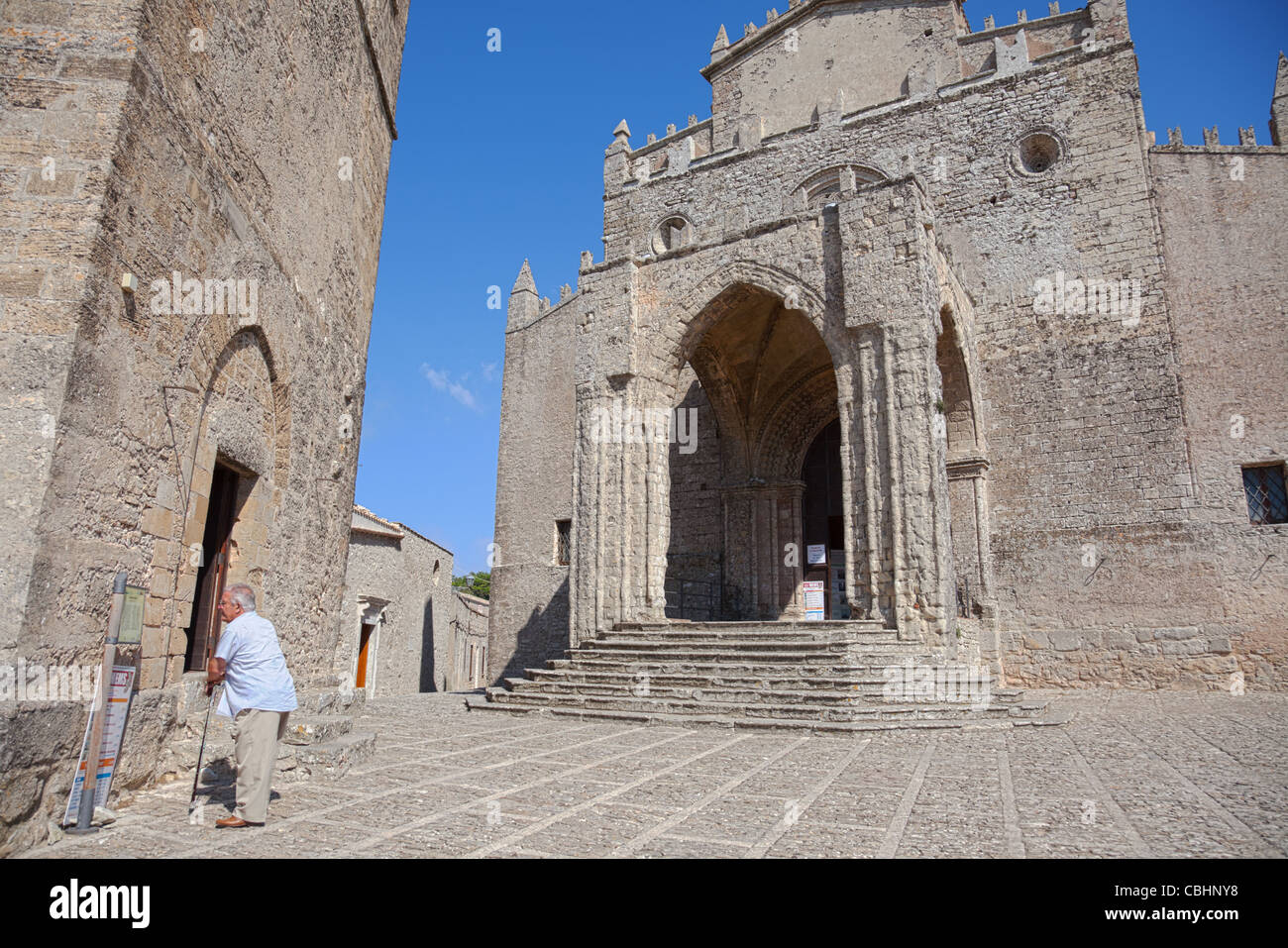 The medieval cathedral Real Duomo in Erice, Sicily with a senior man with a walking stick in front of it. Stock Photo