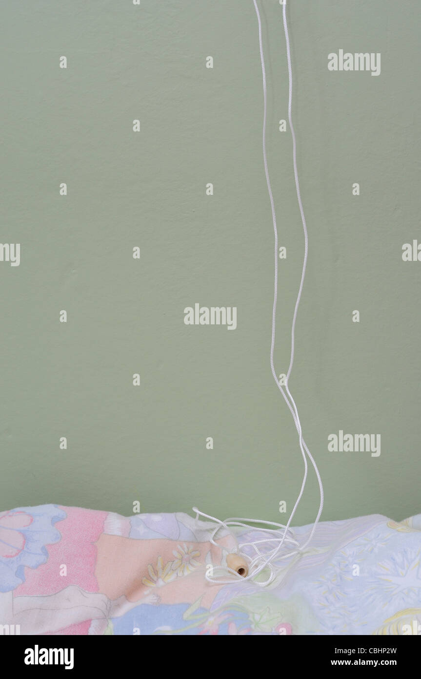 Window blind cord dangling over child's bed. Home safety hazard danger